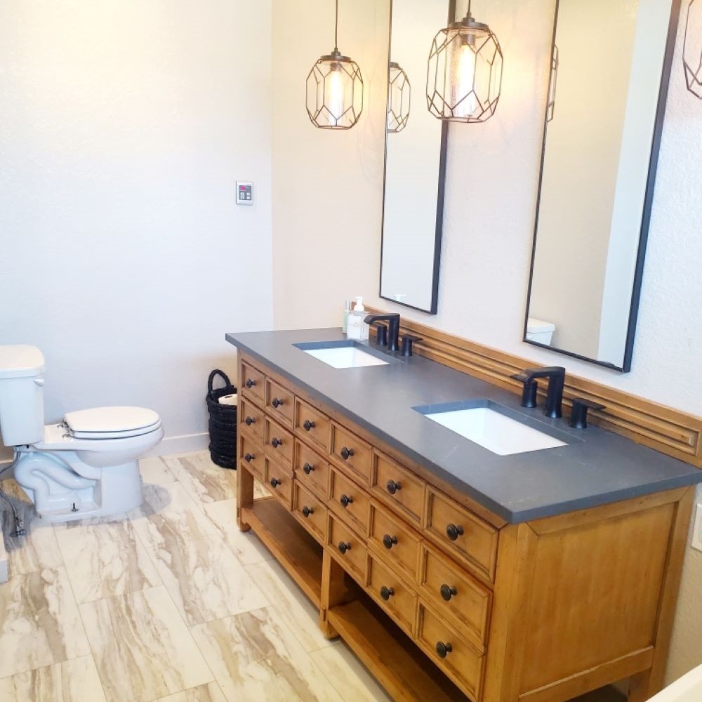 Black bathroom countertops with hanging light fixtures. 
